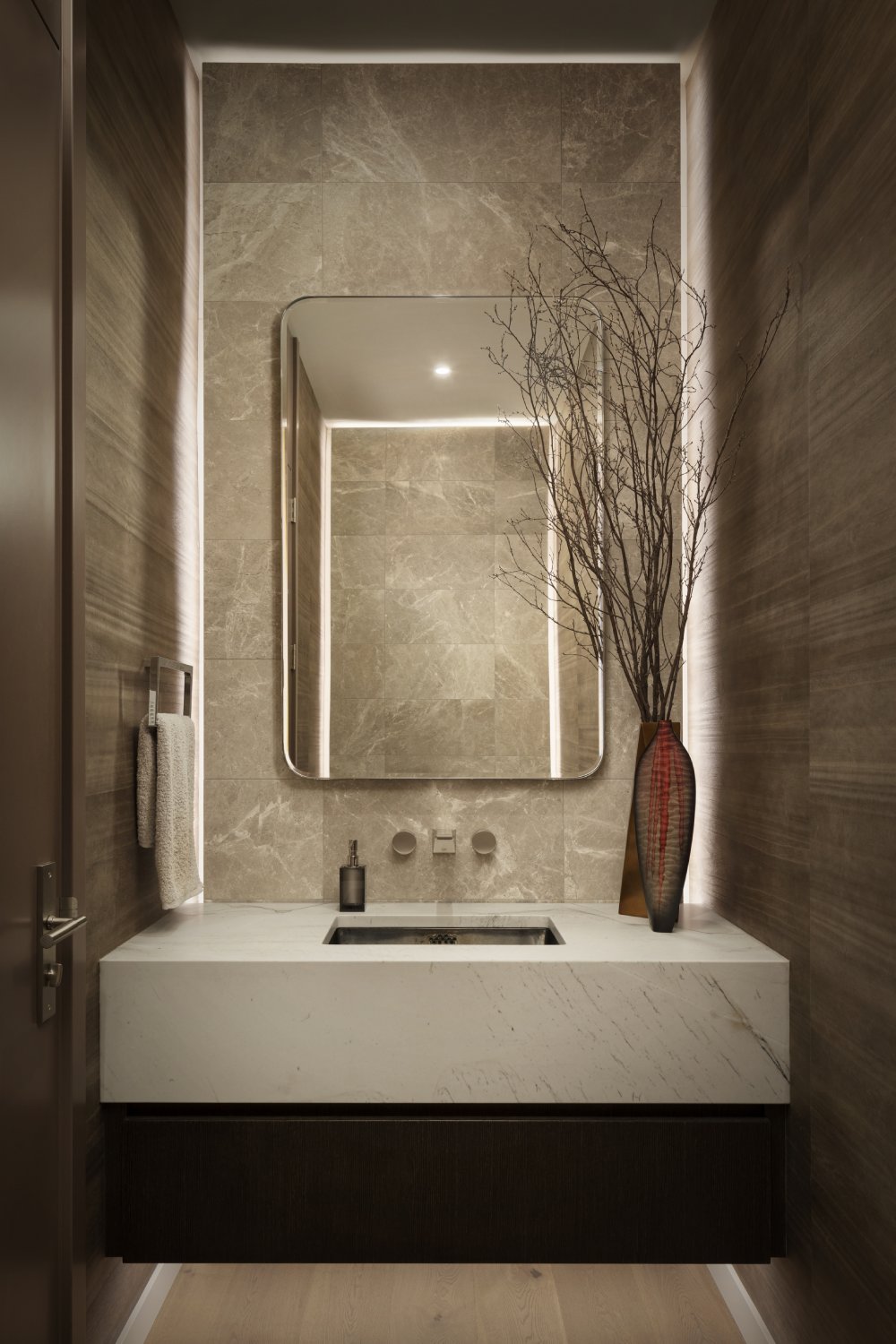 Powder room with floating vanity and brown floor to ceiling tiling.