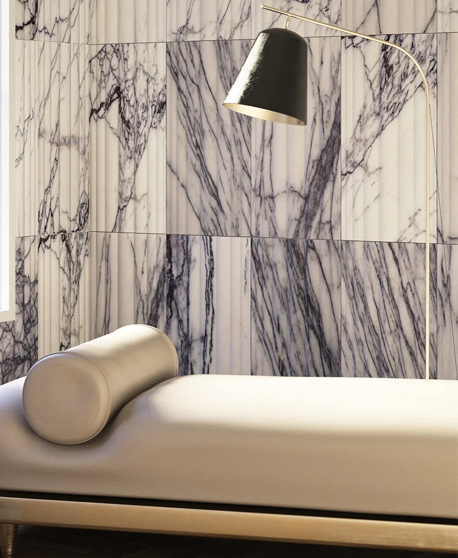 Artistc Tile textured, marble tile wall with a chaise and lamp in front.