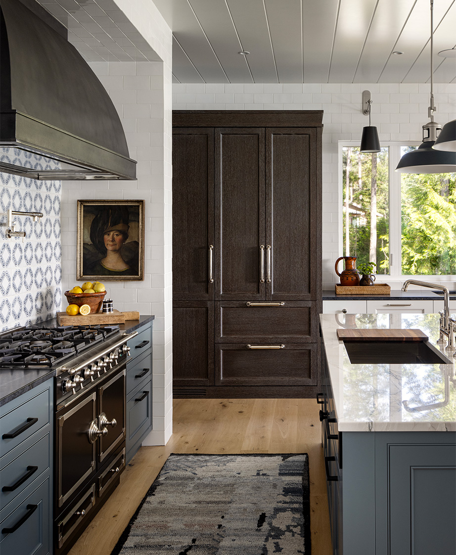 Kitchen with blue cabinetry, dark and light countertops and floor to ceiling wood cabinets in the background.