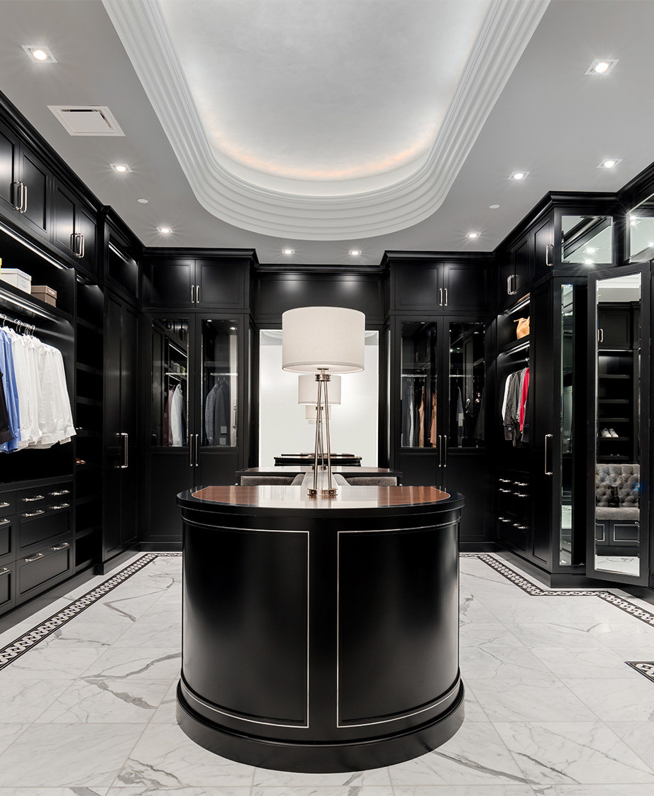 Large walk-in closet with island and black cabinetry.